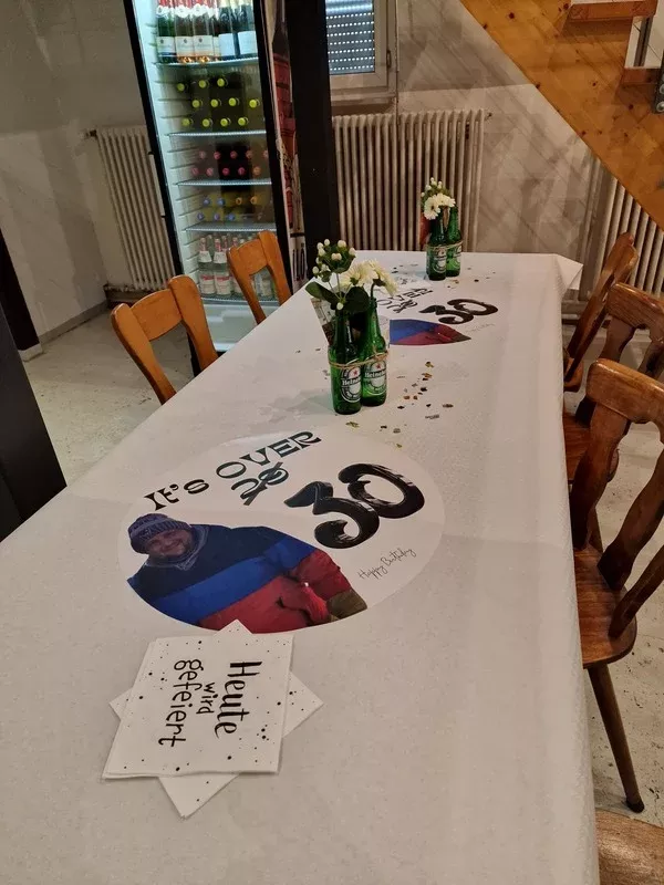 Tischdeko für 30. Geburtstag mit kreativem Motto "It's over 29", personalisierten Fotoaufdrucken, Bierflaschenvasen und festlicher Atmosphäre