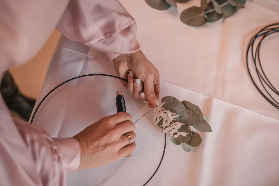 Hintergrund Banner für Breadcrumbs. Chrissy wie Sie mit Draht einen Blumenkranz mit grünen Blättern dekoriert.