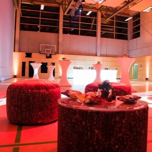 Moderne Eventlocation mit Stehtischen und roten Sitzkissen