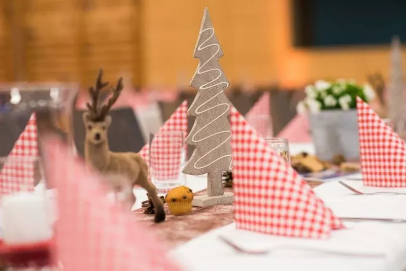 Weihnachtsdeko mit Rentier und Tannenbaum auf gedecktem Tisch für Firmenevent